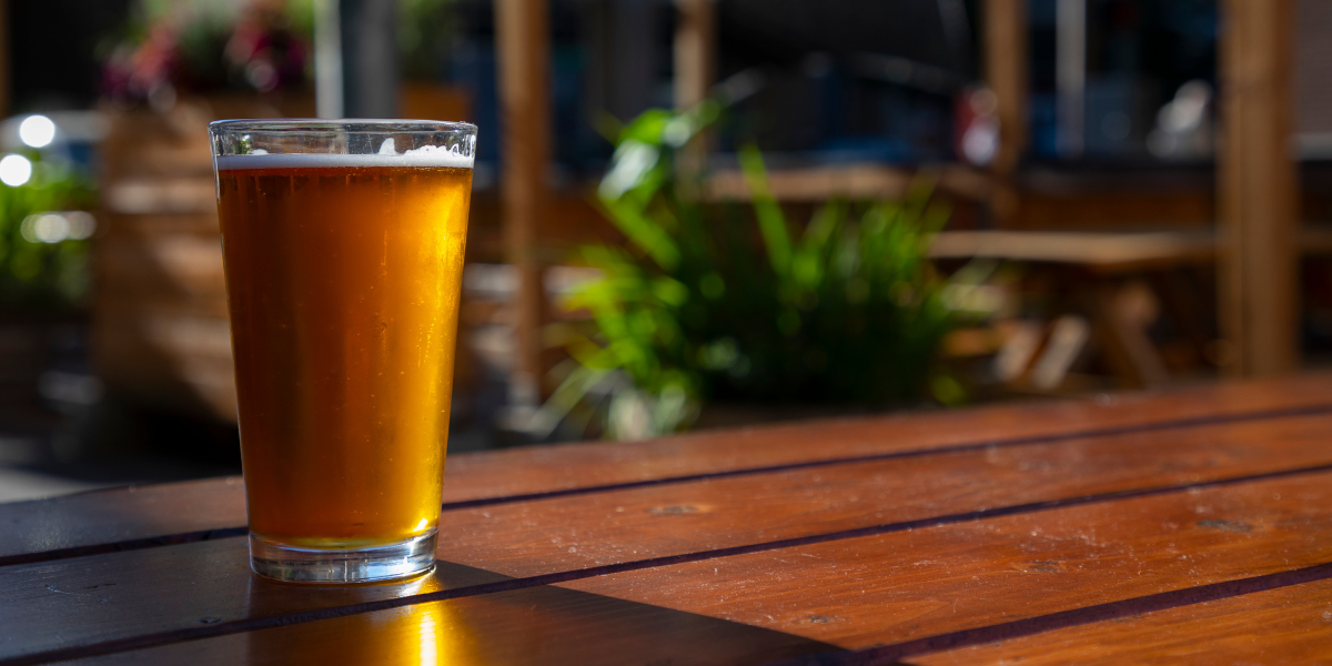 pint of IPA on a pub bench wit the sun reflecting off it
