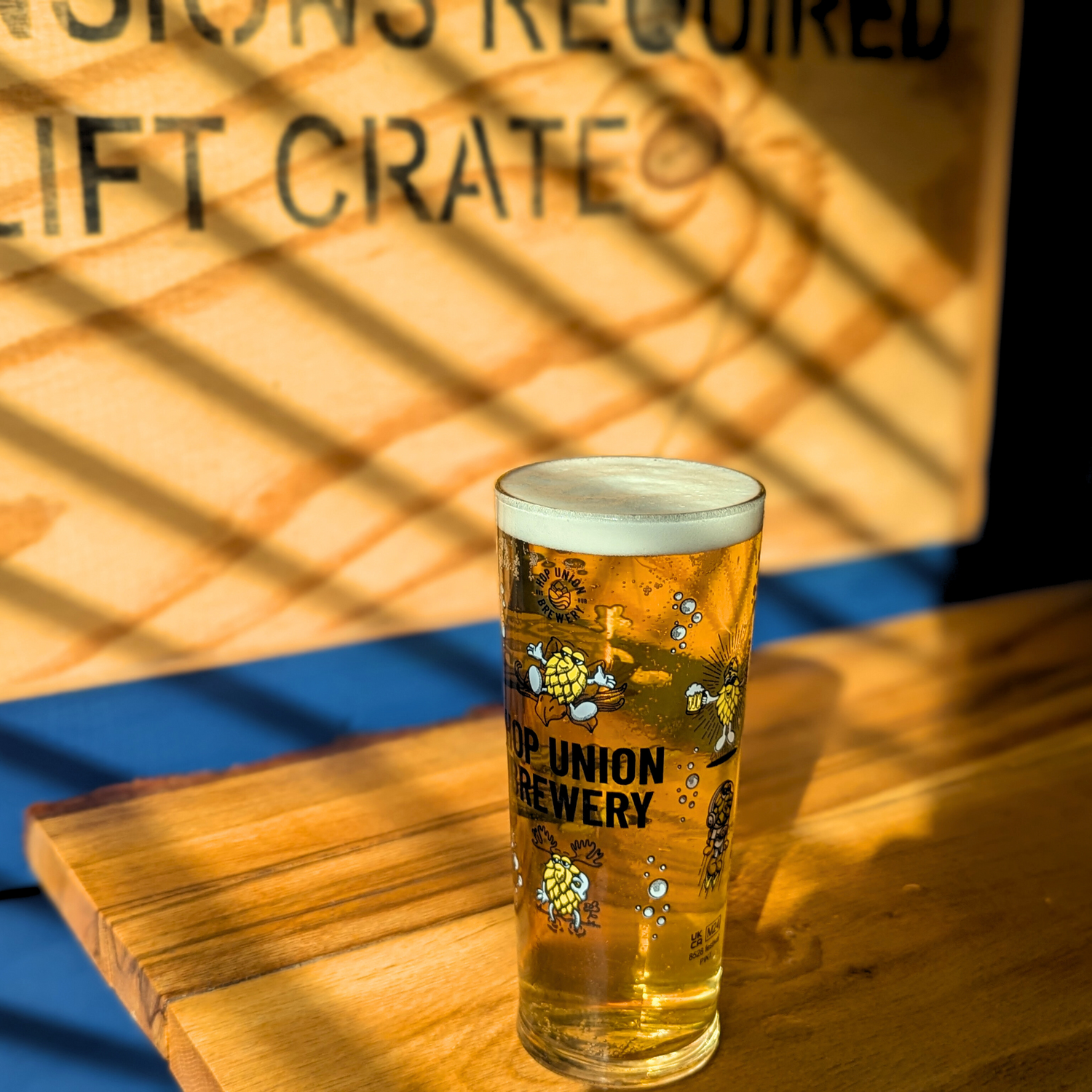 Hop Union Brewery branded glass full of beer in the sun