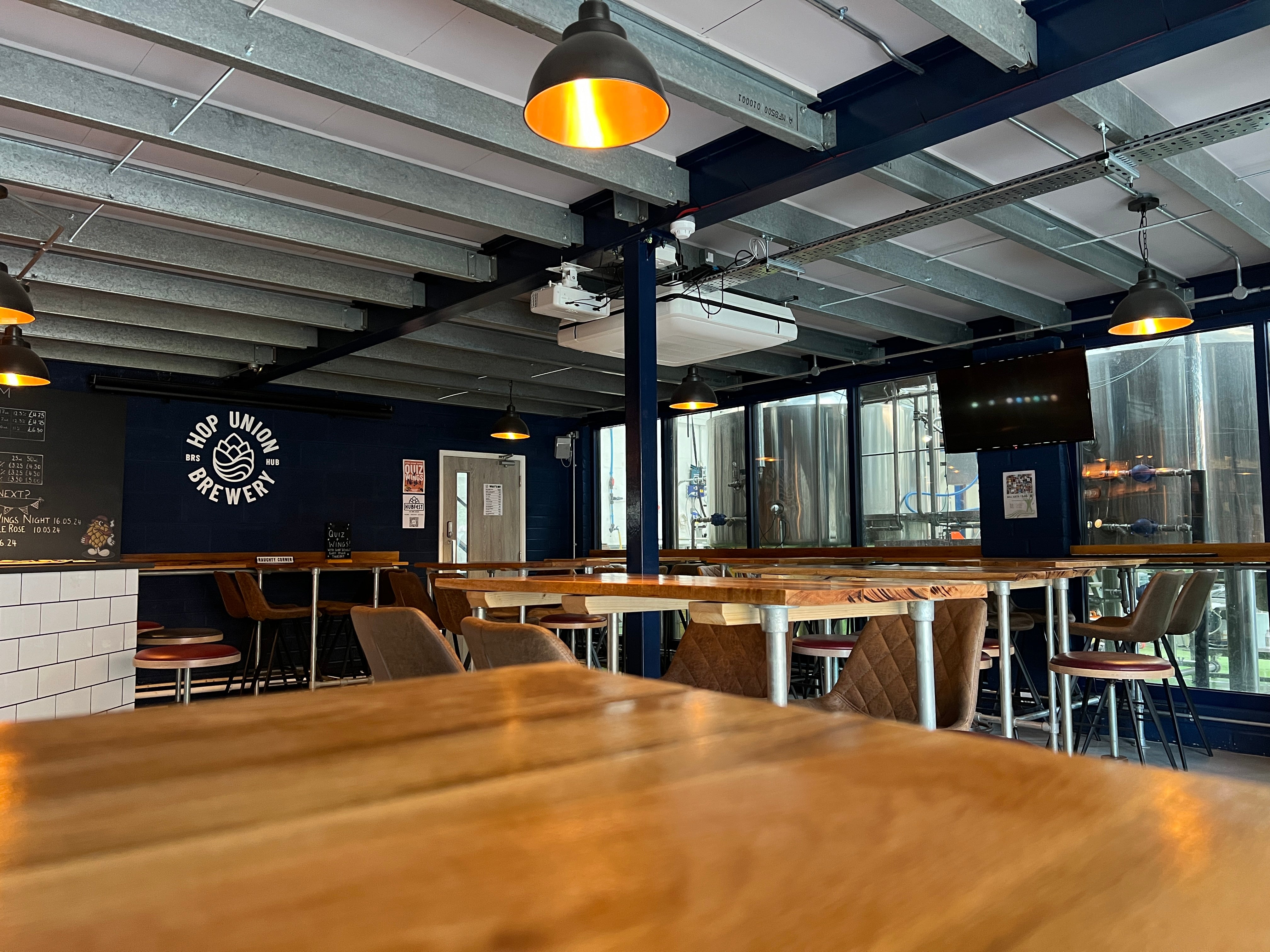 Interior of a Bristol taproom pub with wooden tables, chairs, and a visible logo on the wall.