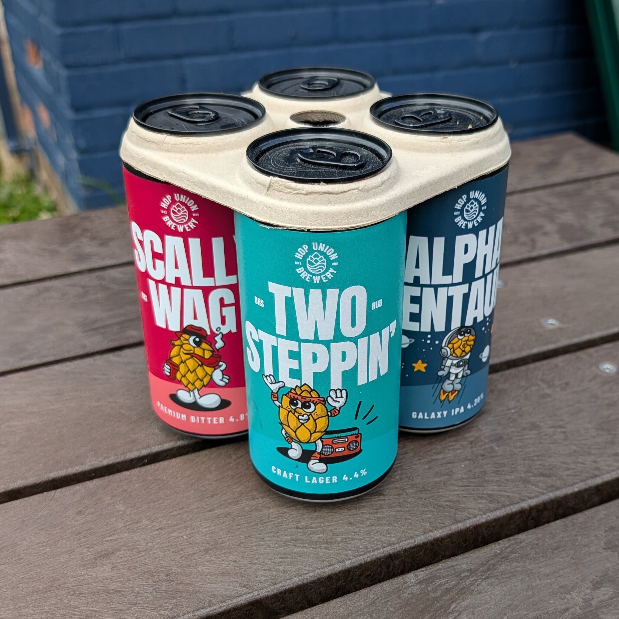 four-pack of colorful beer cans from Hop Union Brewery Bristol on a wooden surface.